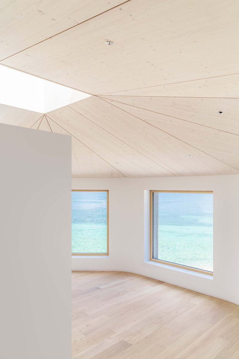 Interior room with pale timber plank ceiling and two timber-framed windows framing turquoise lake views