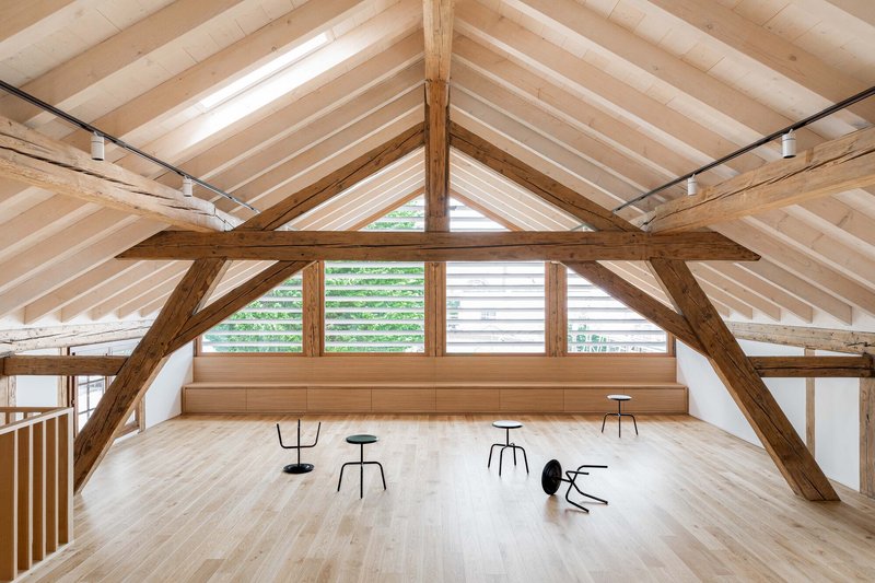 Upper level room with exposed timber trusses and louvered clerestory windows under a pitched roof