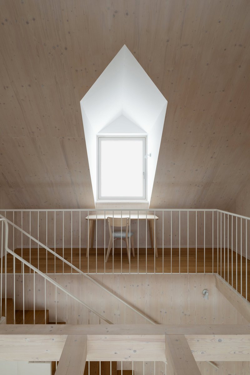 Timber staircase with vertical slat railing below a pentagonal ceiling opening with centered window