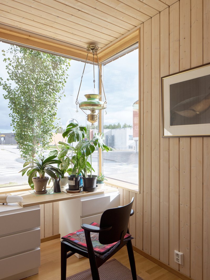 Corner workstation with vertical timber cladding and a row of potted plants on the sill