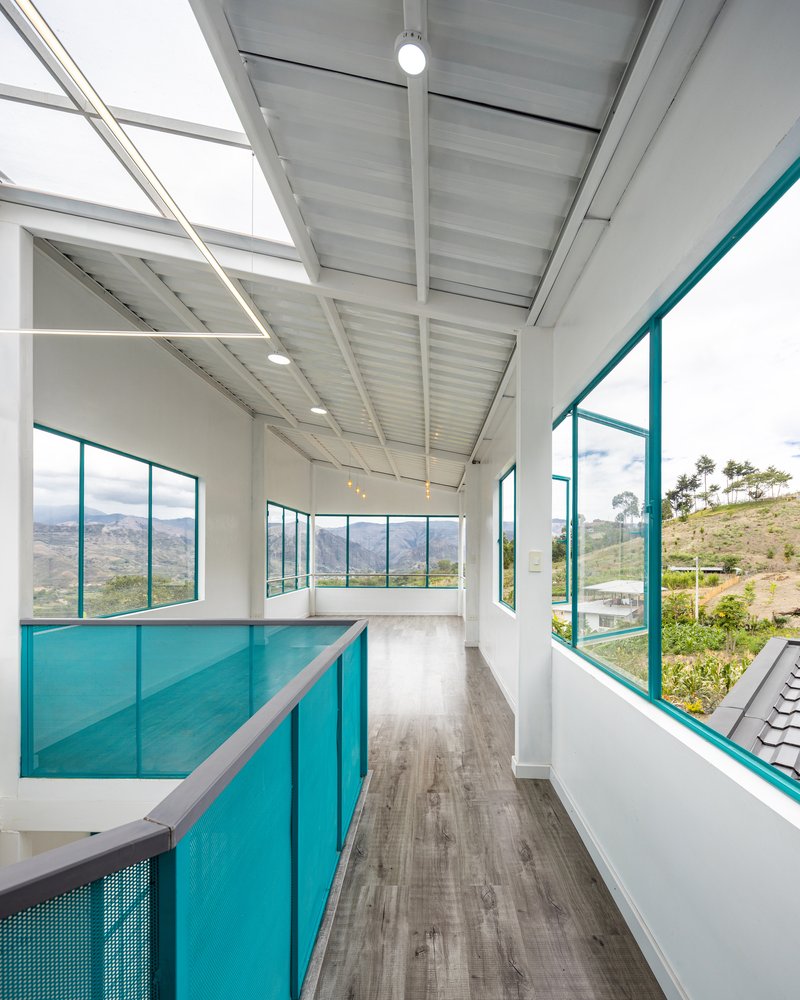 Upper level corridor with turquoise glass balustrade and floor-to-ceiling windows framing mountain views