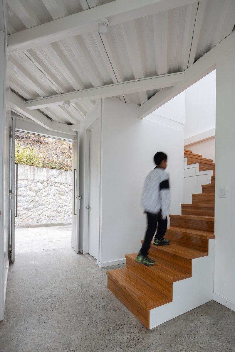 Timber staircase with integrated storage cabinets as a person ascends from the concrete floor