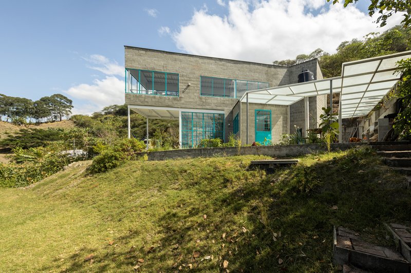 Rear facade with turquoise glazing set into concrete blockwork above a sloping lawn