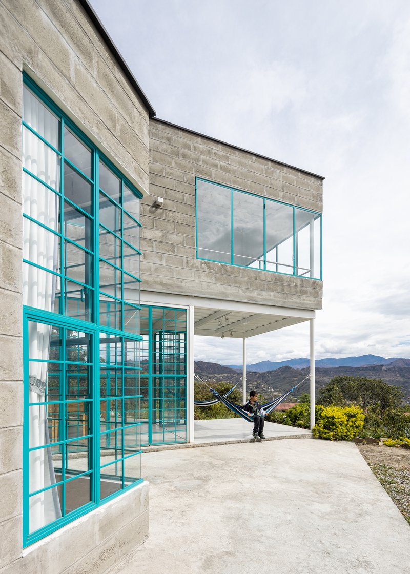 Corner terrace with turquoise steel frames and a person in a hammock overlooking distant mountains