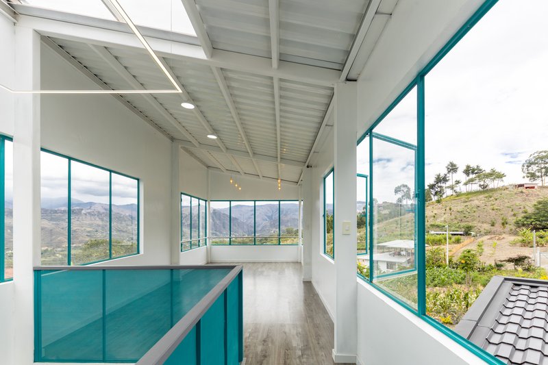 Interior corridor with turquoise glass balustrade and panoramic windows framing the valley landscape