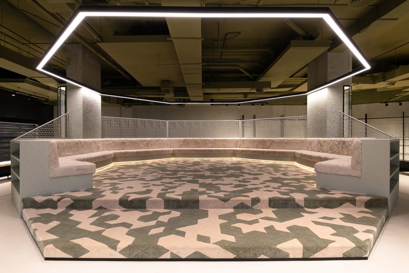 Sunken seating area with curved pink upholstered benches and geometric patterned floor under a pentagonal light fixture