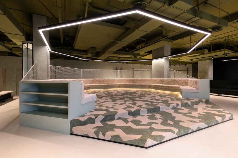 Angled view of the stepped seating pit with integrated shelving units and exposed concrete columns above
