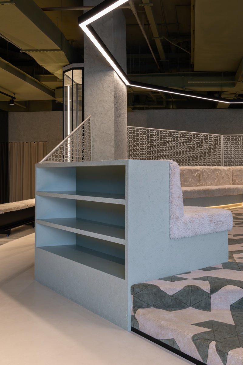 Blue-painted stepped shelving unit beside a patterned tile floor under exposed ceiling structure