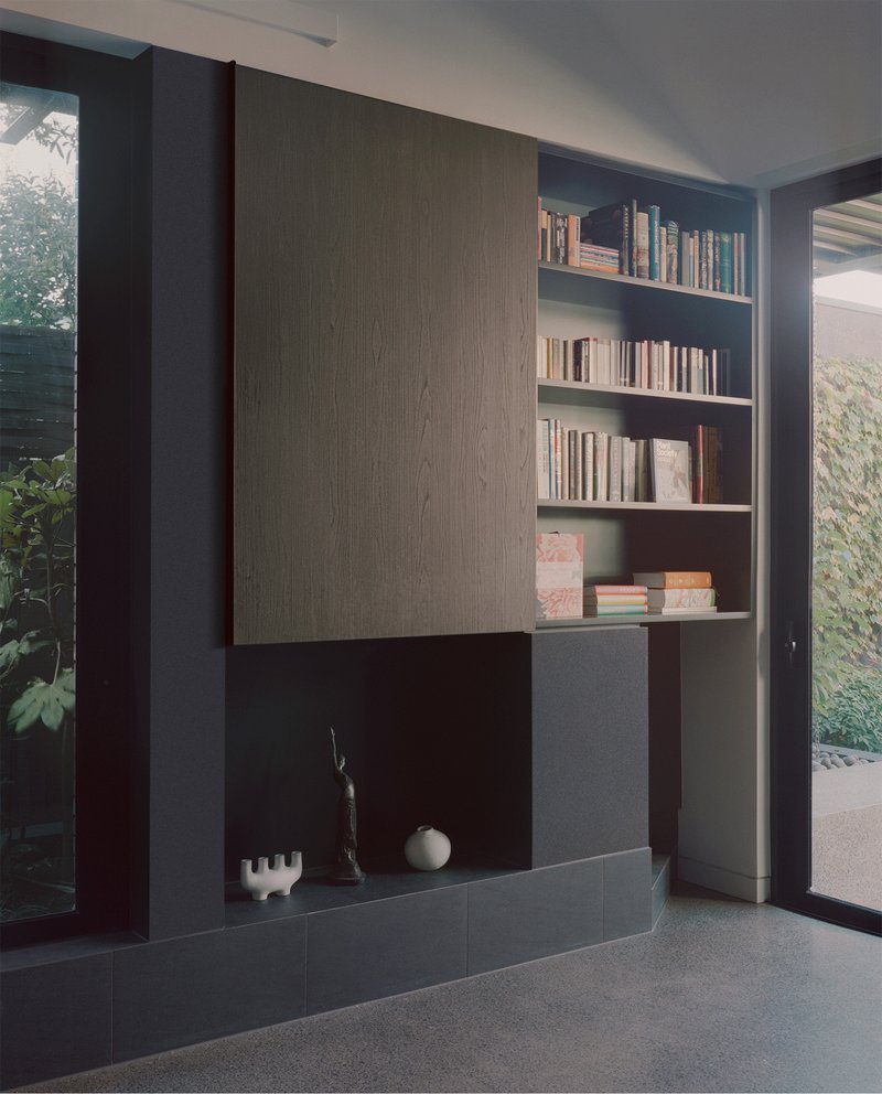 Built-in shelving unit with sliding timber panel beside a garden courtyard view
