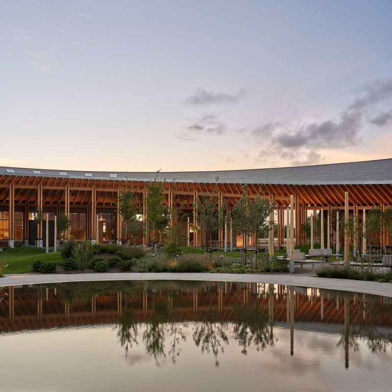 Timber-framed facade with central courtyard and reflecting pool at dusk