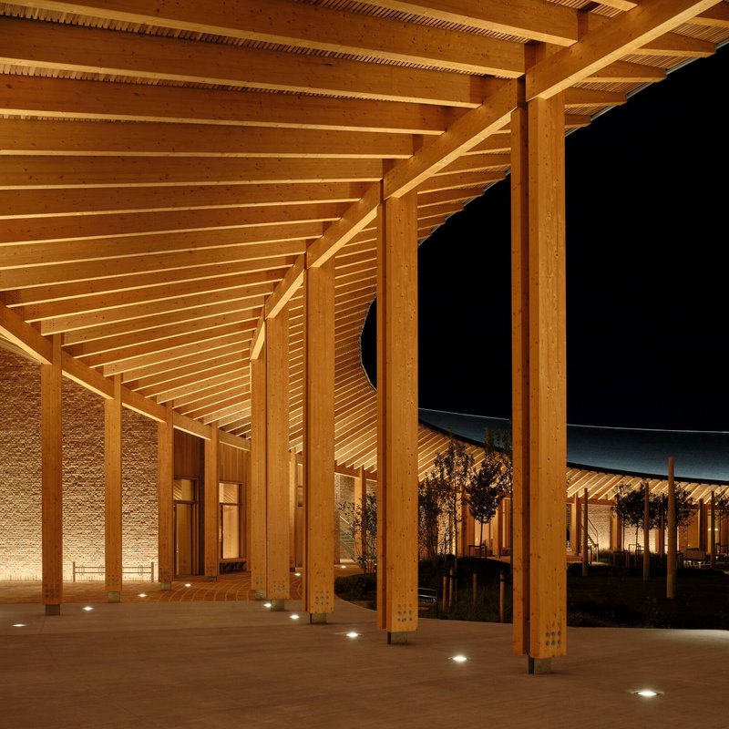 Covered colonnade with exposed timber rafters and floor-mounted uplights at night