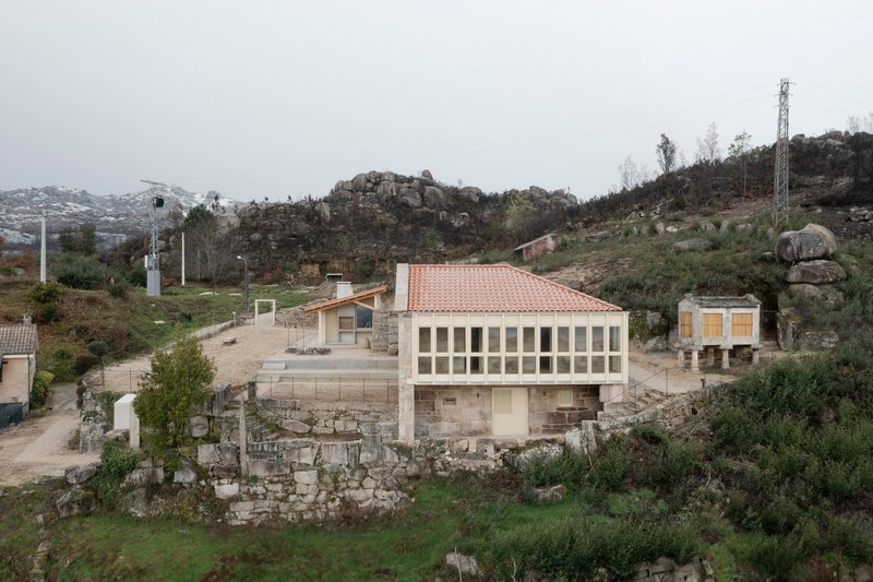 Cluster of stone and timber structures with terracotta roofs on a rocky hillside in overcast weather
