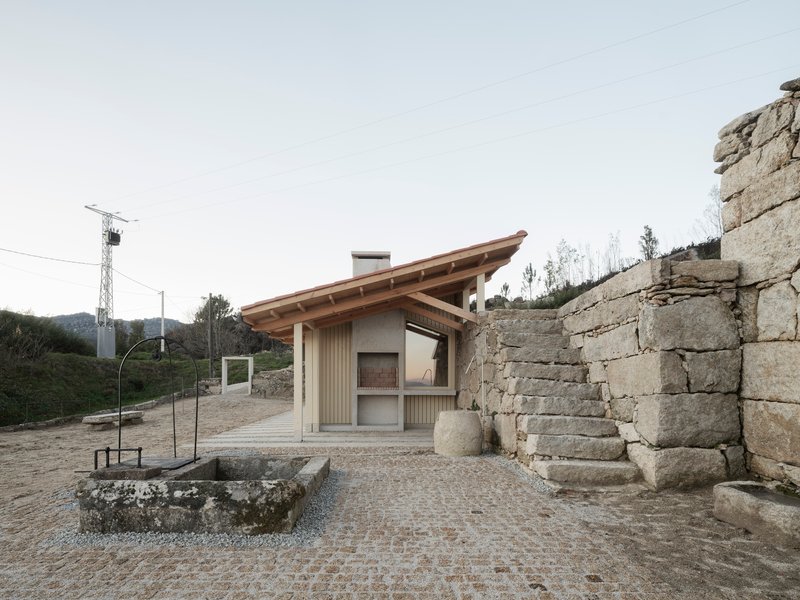 Timber-clad structure with vertical siding and sloped roof against ancient stone walls