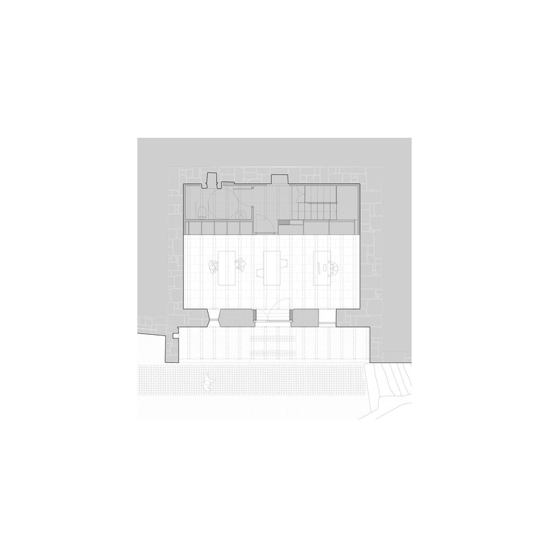 Ground floor plan drawing showing a rectangular volume with courtyard and surrounding paved areas