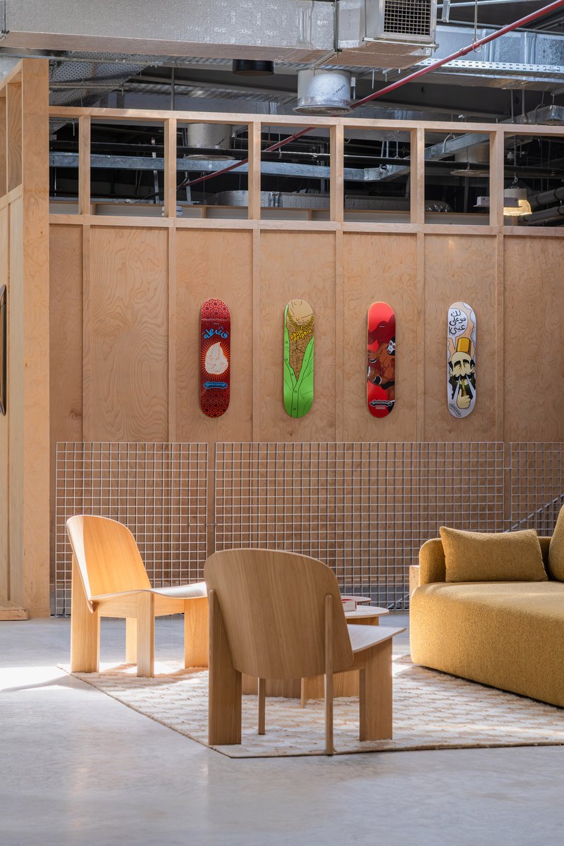 Plywood partition with four skateboards mounted above a mosaic tile wainscot and exposed ductwork overhead