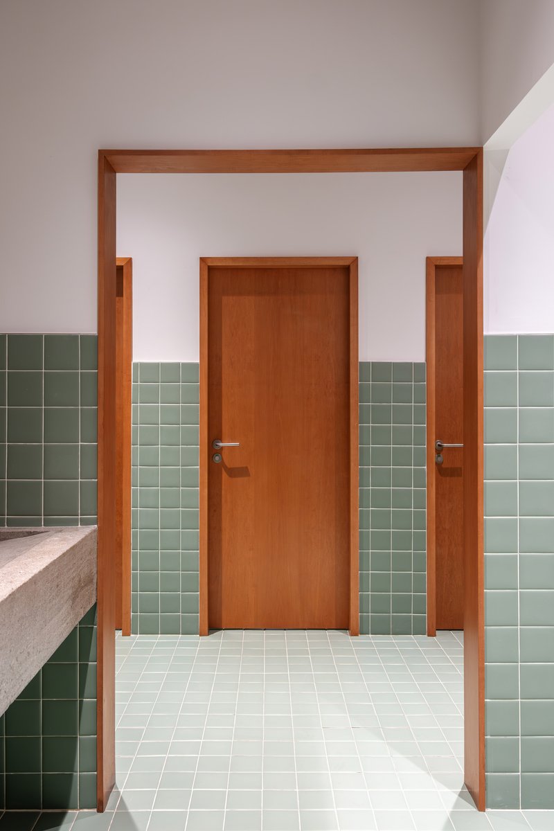 Hallway with timber door framed by sage green tile wainscoting and cream terrazzo countertop