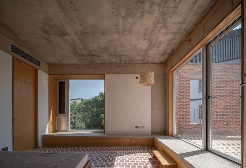 Built-in timber window seat with view to courtyard and exposed concrete soffit casting geometric shadows