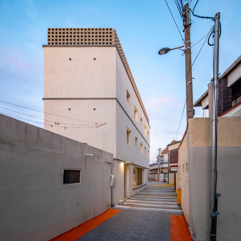View down the shared alleyway with yellow and grey paving at dusk beneath overhead wires