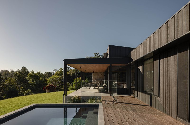Rear terrace with timber deck and lap pool overlooking the landscape at dusk
