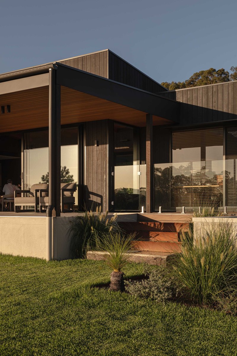 Entry courtyard with planted beds in red soil beneath the cantilevered roof soffit