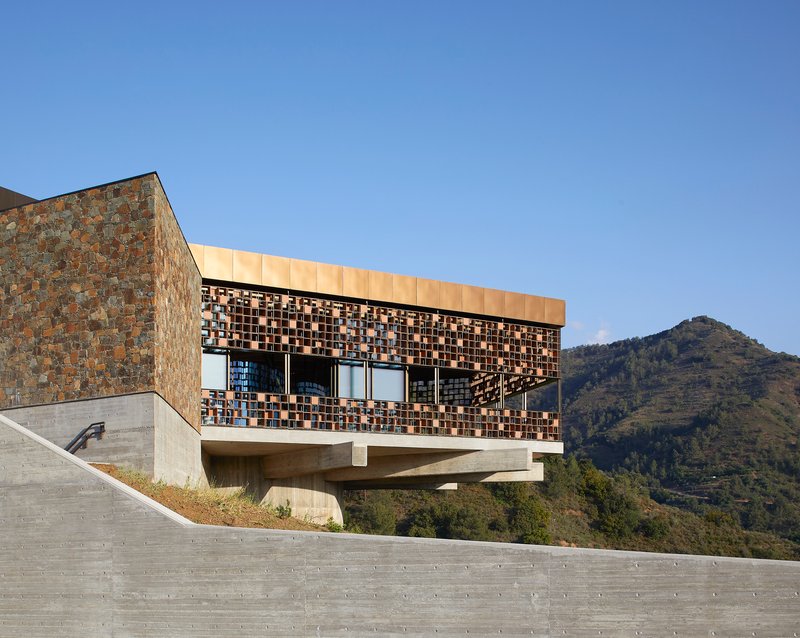 Upper volume with patterned tile screen and ribbon windows overlooking mountain terrain in daylight