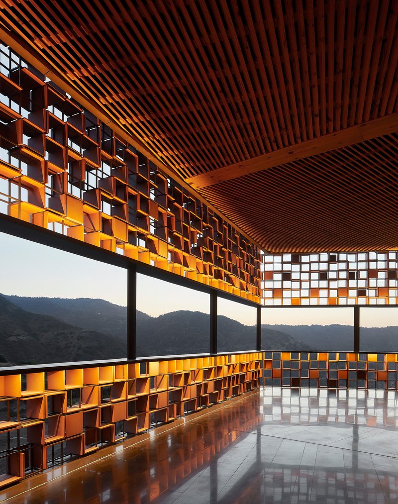 Interior corner with slatted timber ceiling and perforated copper screen filtering afternoon light