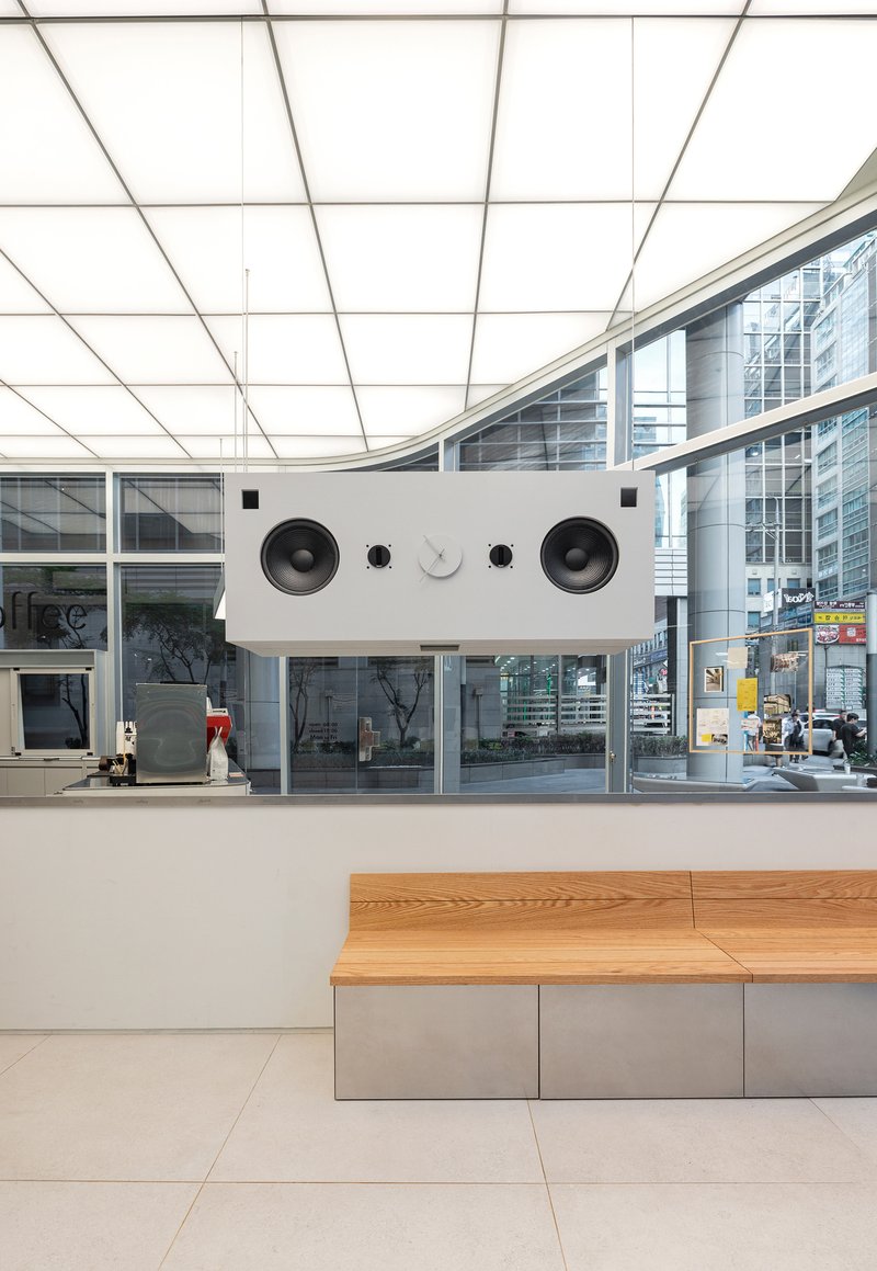 Service counter with integrated speaker grilles beneath a curved backlit ceiling grid