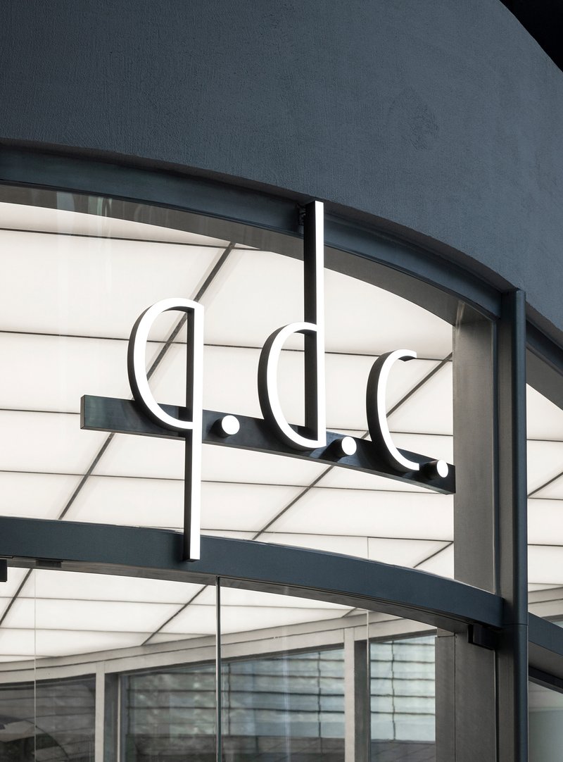 Illuminated signage and horizontal banding detail on the curved storefront canopy