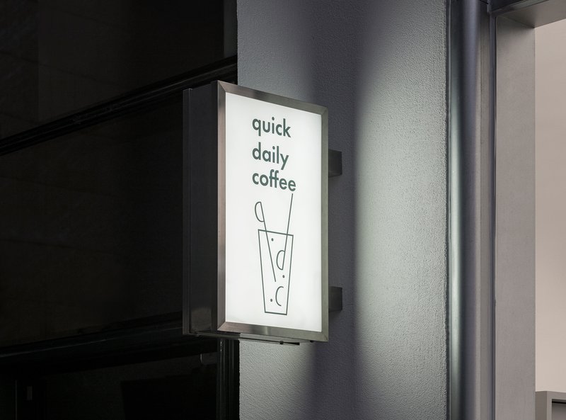 Backlit wall-mounted signage panel against a textured gray exterior wall