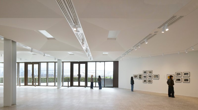 Gallery space with polished concrete floor and visitors viewing framed photographs along white walls
