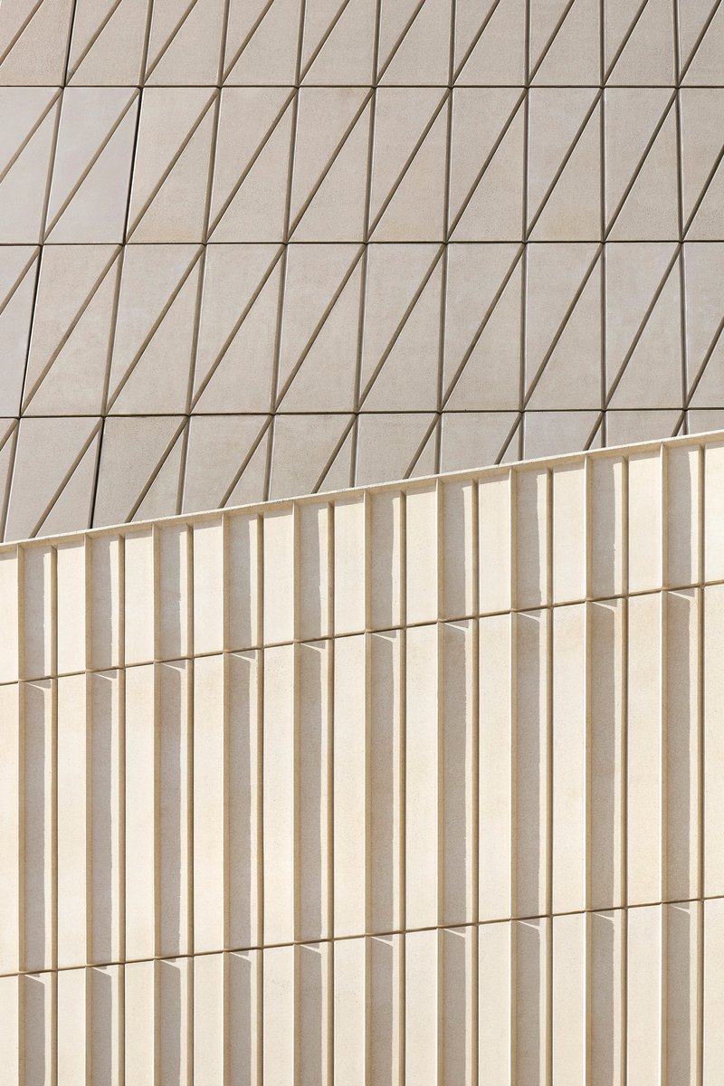 Two facade surfaces with contrasting patterns of diagonal grooves and vertical flutes meeting at a corner