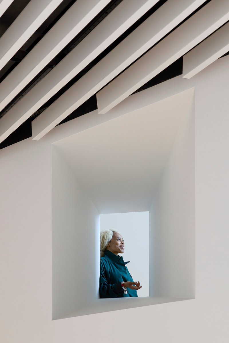 Deep framed window opening with a visitor looking outward beneath angled ceiling louvers