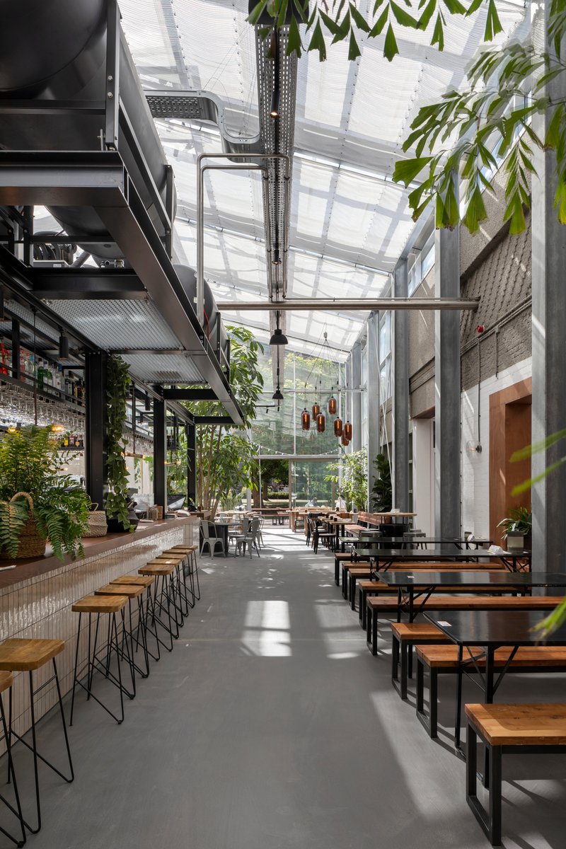 Interior courtyard with translucent roof panels above dining tables and hanging plants