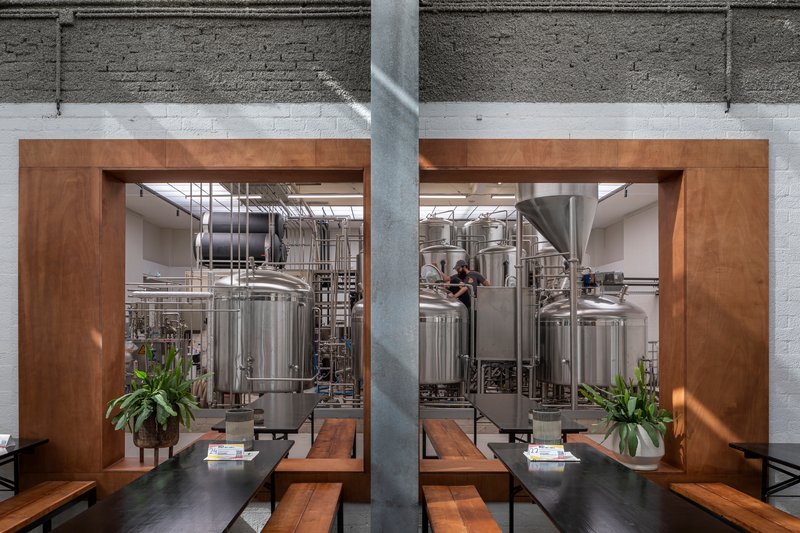 Timber-framed openings offering views into the brewery production floor from the seating area