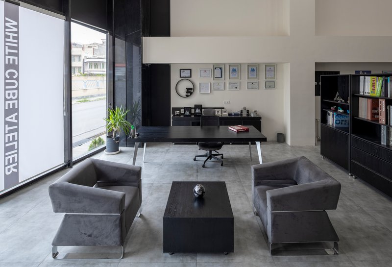 Reception area with grey upholstered chairs and black furniture beneath full-height glazing with lettering