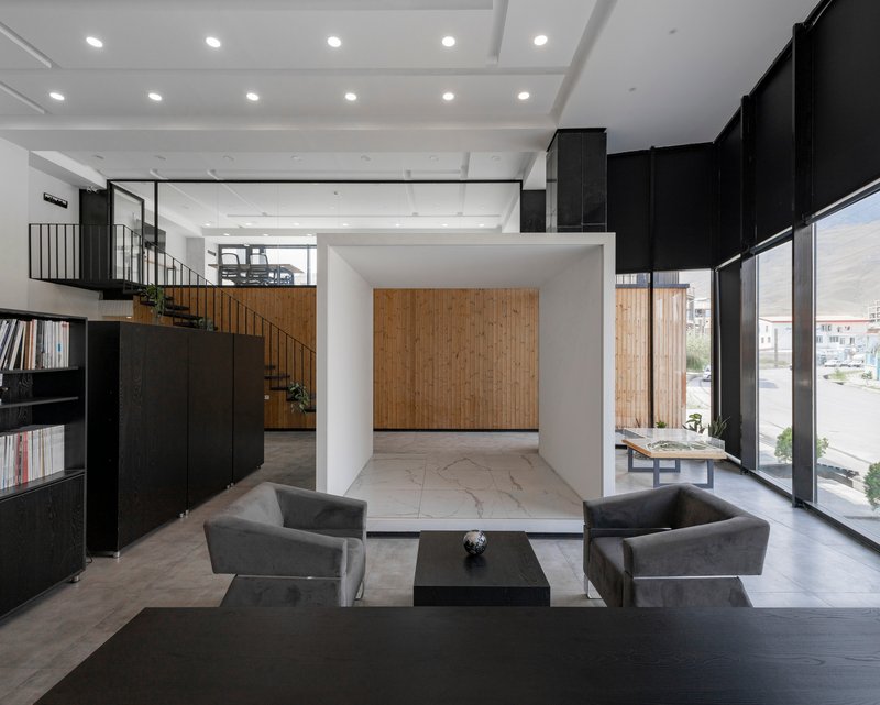 Double-height lobby with coffered white ceiling, black walls, and timber accent wall visible beyond