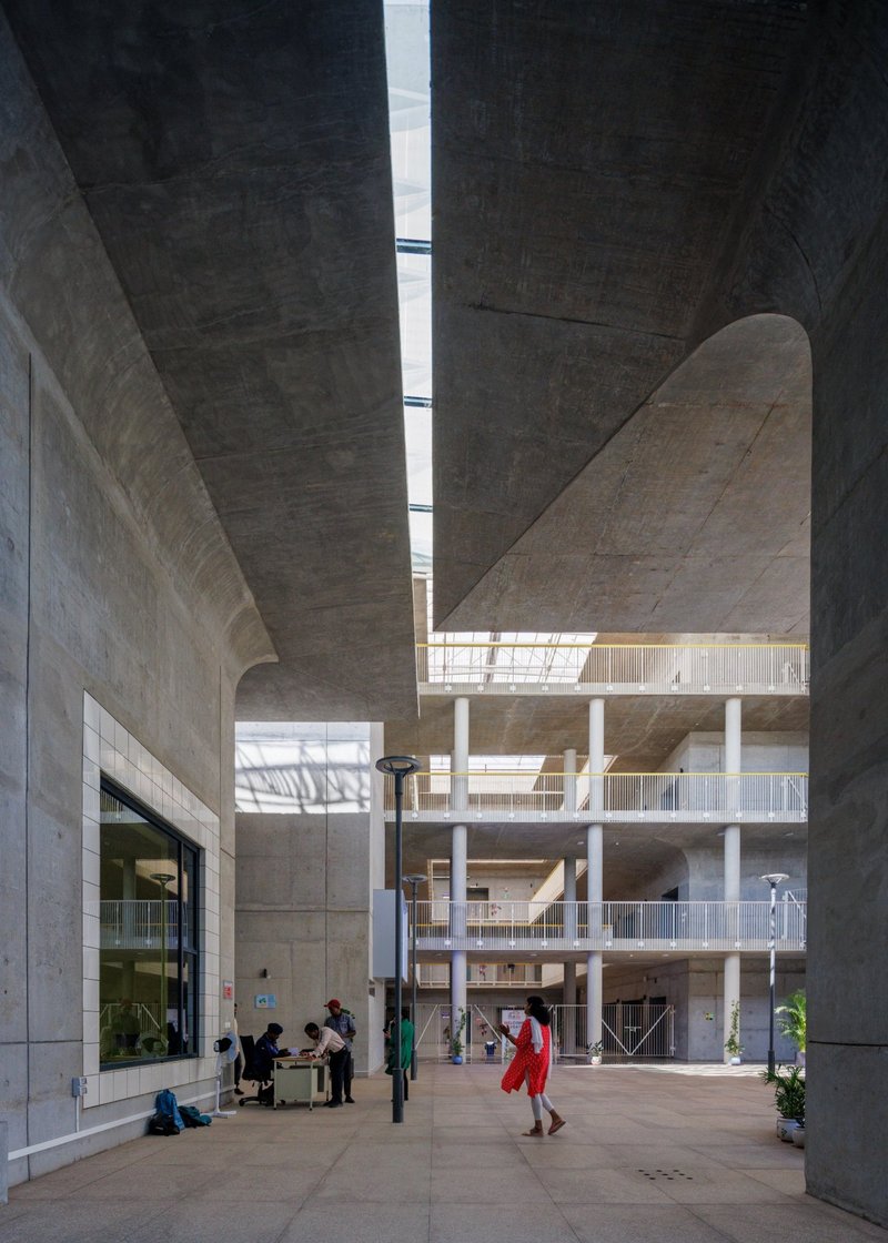 Multi-story atrium with exposed concrete ceilings and curved vaults illuminated by a central skylight slot