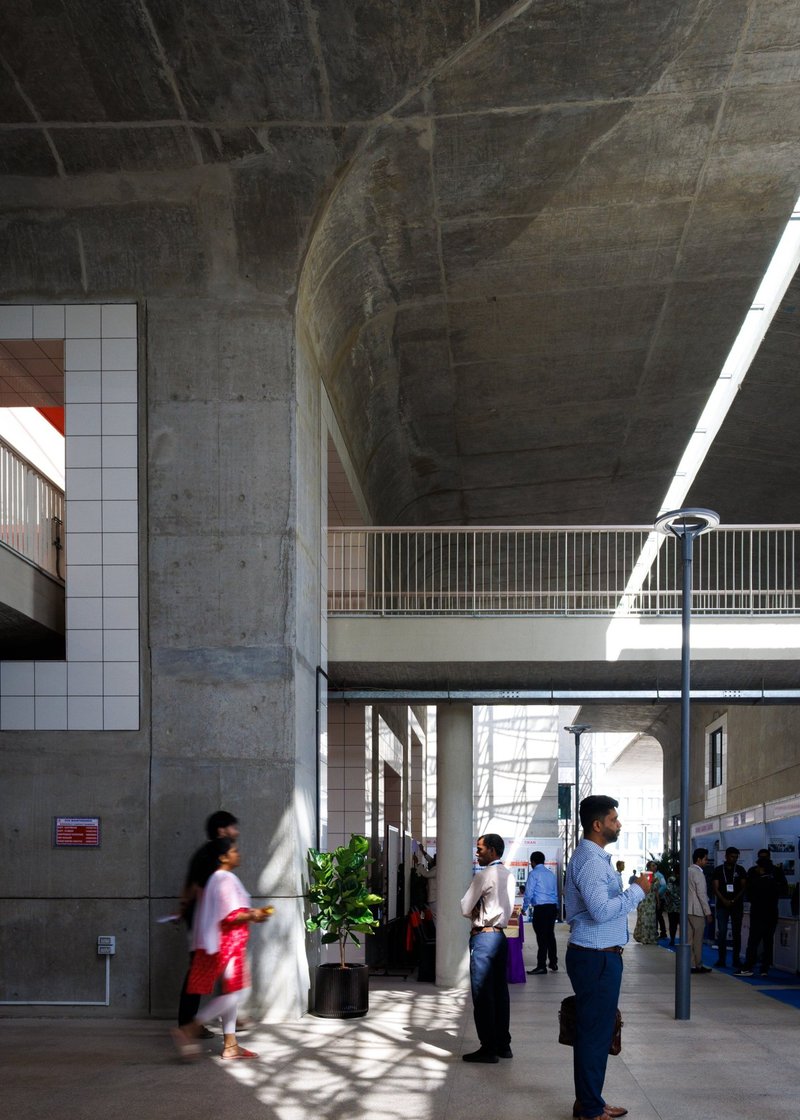 Ground floor circulation space with concrete columns and metal railings beneath an arched vault