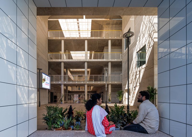 View through the central courtyard showing stacked balconies framed by white tile-clad walls with seated visitors