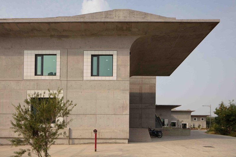 Exterior view of the cantilevered concrete canopy with white tile-framed windows under an overcast sky