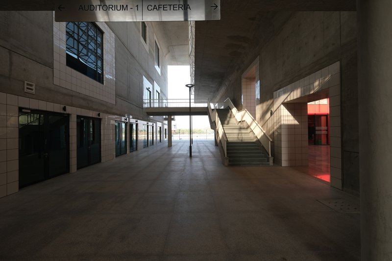 Interior lobby with central staircase and directional signage under concrete vaults with afternoon light