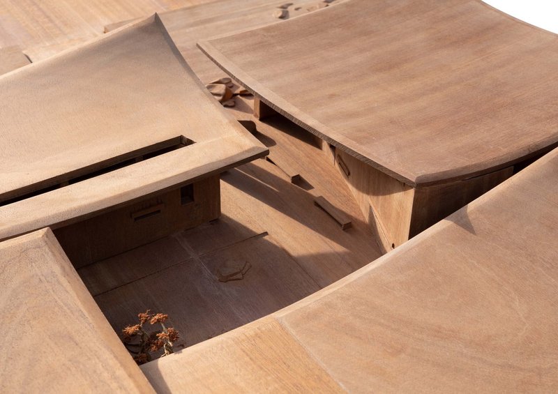 Physical model showing intersecting roof planes and a sunken courtyard with a small tree