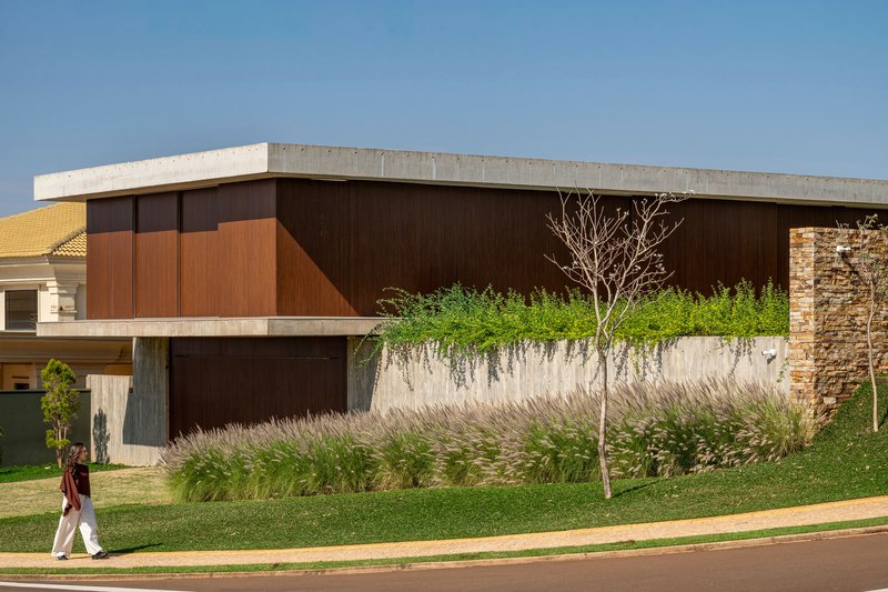 Upper-level timber facade with planted green roof terrace and pedestrian on the sidewalk below