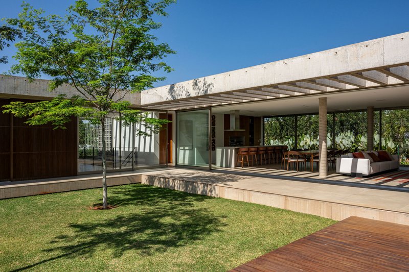 Courtyard with a young tree and concrete beam canopy connecting glass-walled interior volumes