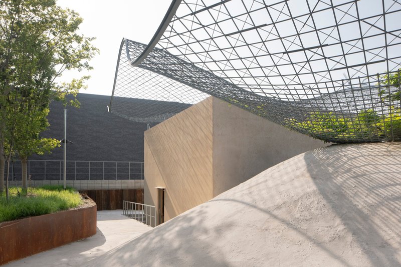 Entrance courtyard with rammed earth walls and corten planter beneath the triangulated steel canopy