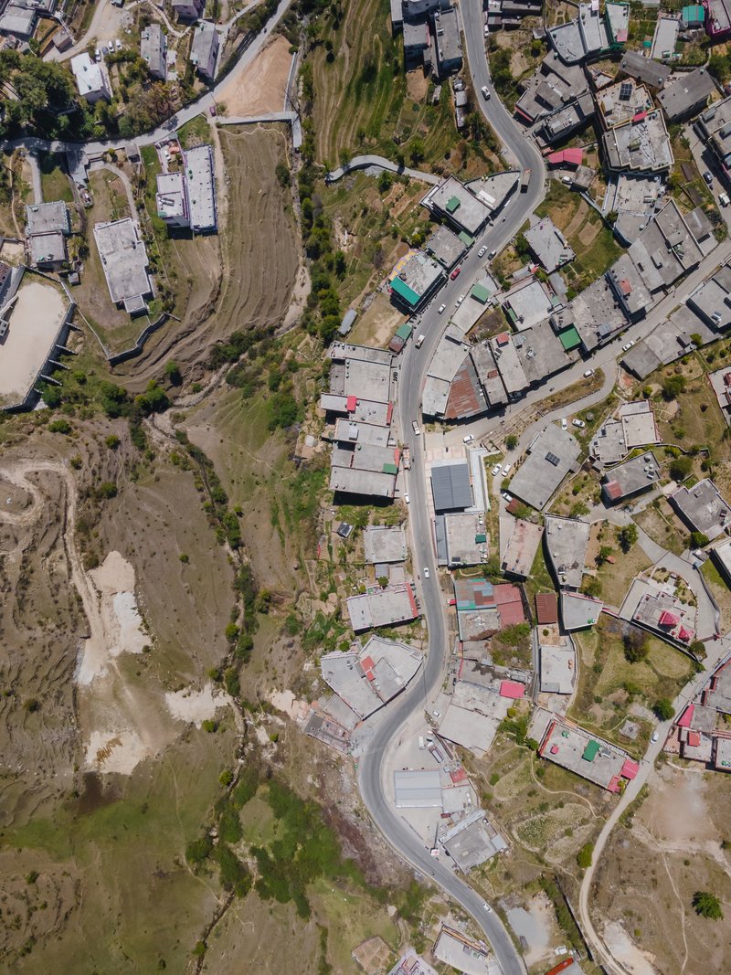 Aerial view of a winding road threading through hillside houses and agricultural terraces