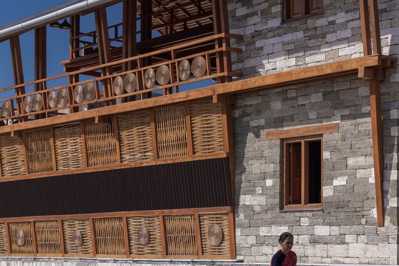 Close-up of the woven timber infill panels and carved wooden medallions with a passerby below