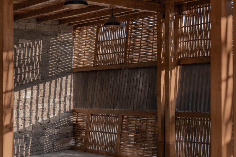 Close-up of woven bamboo panels set within timber framing with corrugated metal backing in sunlight