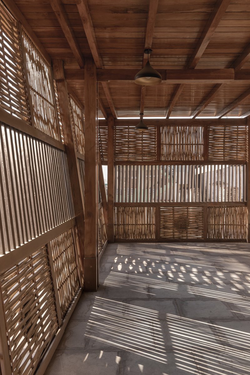 Interior with slatted timber screens filtering afternoon sunlight onto the concrete floor