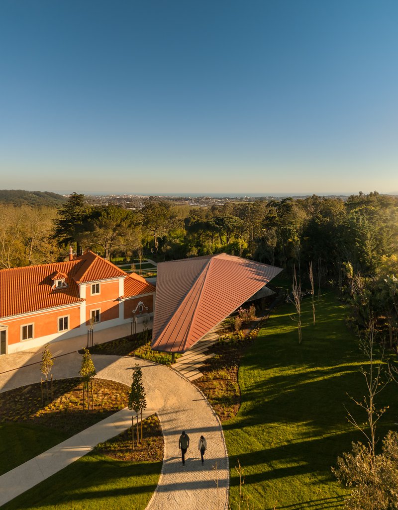 Aerial view of the red tile roofs and curved pathways through landscaped grounds with two figures walking